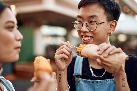 Happy guy and lady eating sweet grill cornの写真素材