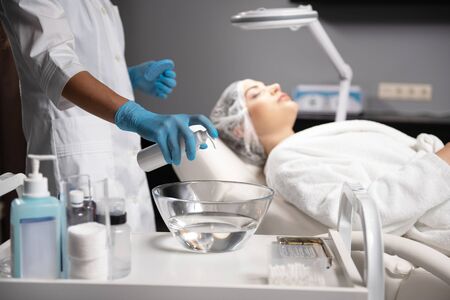 Beautician in sterile gloves preparing cleansing liquid for beauty procedureの写真素材