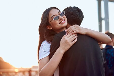 Pretty asian girl hugging with guy on sunset lightの写真素材