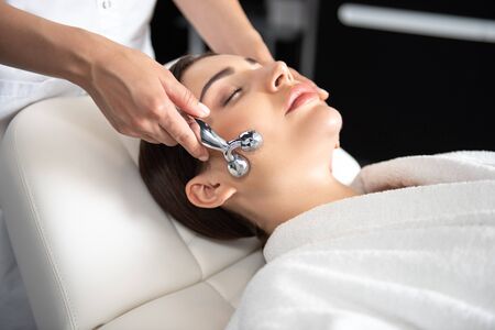 Serene young woman receiving face massage at beauty salon