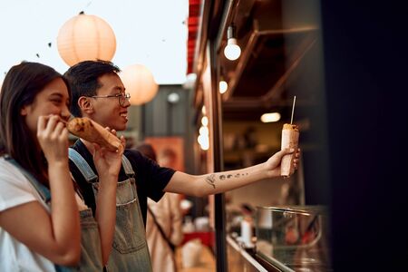 Happy asian couple buying corn in street cafeの写真素材