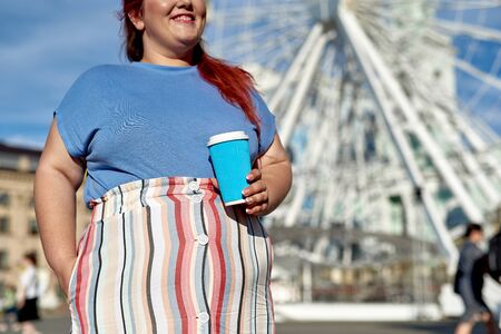 Young and fat woman with paper cup in the cityの写真素材