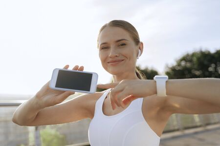Happy athletic female point on mobile phone