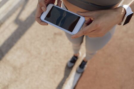Athletic lady taking photo of road on mobile phone