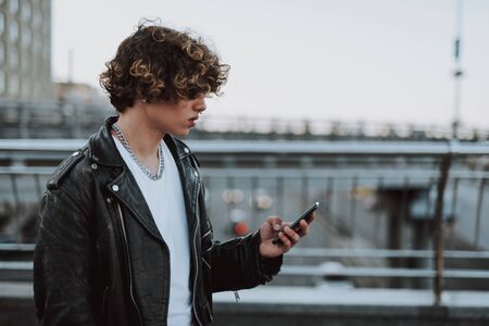 Young biker on the bridge using his smartphoneの写真素材