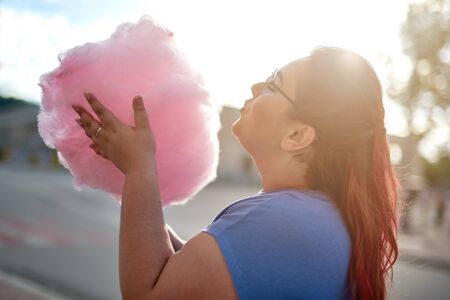 Fat young woman walking with cloud of candy-flossの写真素材