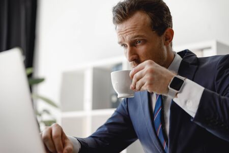 Man drinking coffee while looking at the screenの写真素材