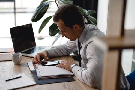 Side view of the man with gadget at his workplaceの写真素材