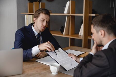 Thoughtful man reading contract in employers officeの写真素材