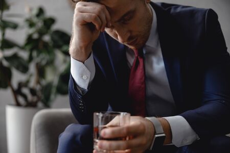 Tired businessman closing eyes and holding whiskyの写真素材