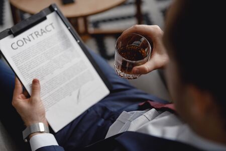 Selective focus of the man with glass of whisky reading contractの写真素材