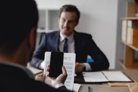 Man holding smartphone in front of the contractの写真素材