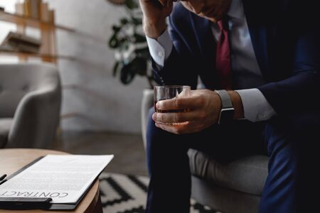 Businessman leaning to the glass of drink while sitting with contractの写真素材