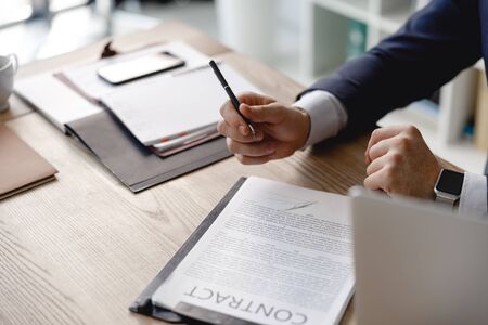 Hands of businessman with pen and contract on the table