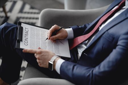 Clipboard with contract and black pen in hands of manの写真素材