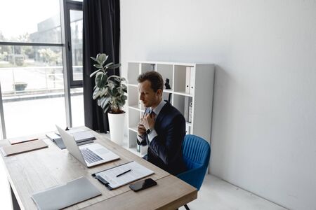 Businessman adjusting his tie while being in the officeの写真素材