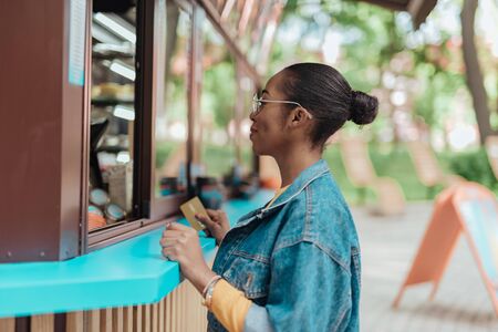 Happy afro-american lady standing near coffee shopの写真素材