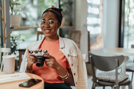 Smiling young afro-american woman with photo cameraの写真素材