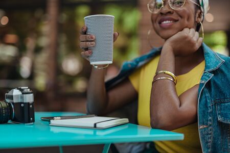 Happy afro-american lady sitting in cafe with beverageの写真素材