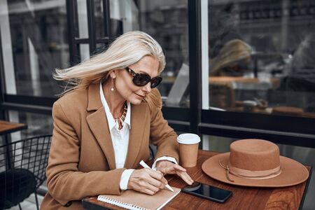 Woman using smartphone and making notes stock photoの写真素材