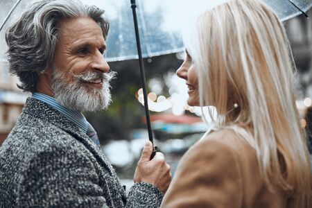 Mature couple standing under one umbrella stock photoの写真素材