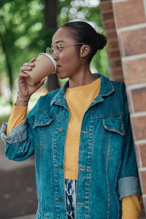 Young afro-american woman drinking coffee from paper cup