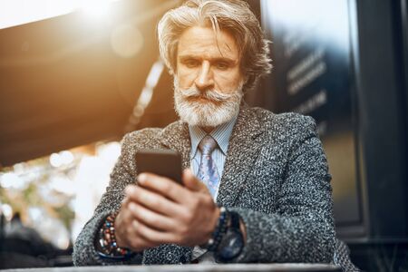 Mature man concentrated on smartphone stock photoの写真素材