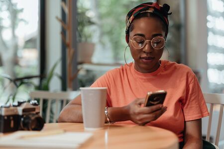 Young afro-american woman using smartphone in cafeの写真素材