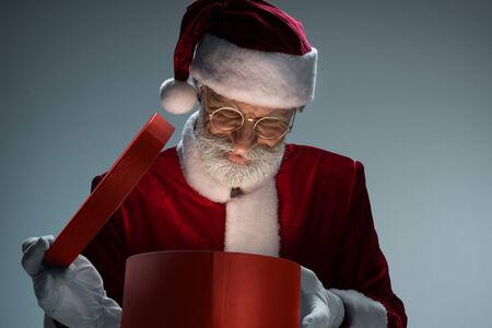 Elderly Santa Claus looking at opened gift boxの写真素材