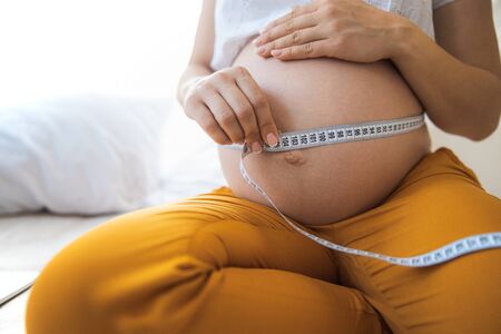 Pregnant lady checking growth of her bellyの写真素材