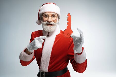 Mature Santa Claus pointing at paper keyの写真素材