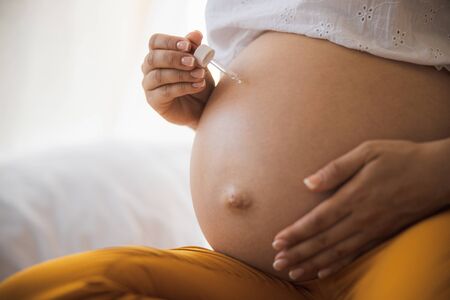 Pregnant woman applying vitamin serum on her belly