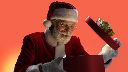 Senior Santa Claus looking inside opened gift boxの写真素材