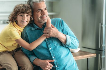 Little son hugging mature father at homeの写真素材