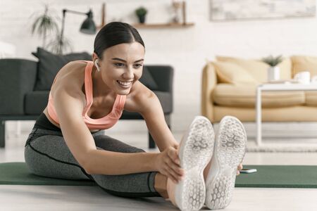 Cheerful woman stretching after home workout stock photo