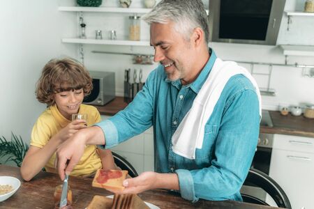 Father with son making toast on breakfastの写真素材
