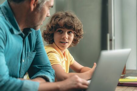 Mature father and son making homework, using laptopの写真素材