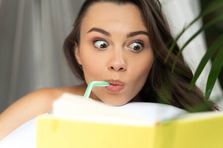 Cute young woman reading book and drinking cocktailの写真素材