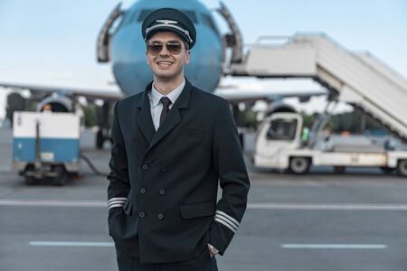 Handsome smiling pilot in uniform walking in airportの写真素材