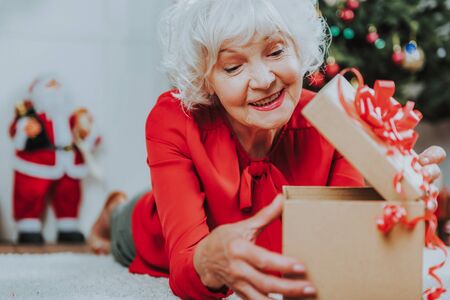 Happy gray-haired woman is looking in boxの写真素材