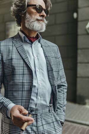 Stylish senior man in sunglasses holding cigarの写真素材