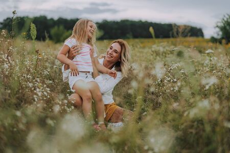 Happy lady hugging her small daughter in fieldの写真素材