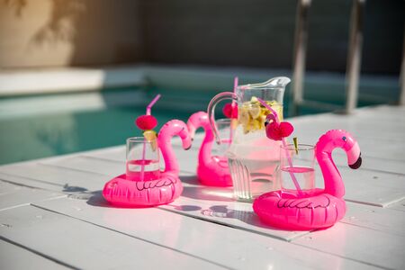 Cold drink with pink inflatable flamingo on the tableの写真素材