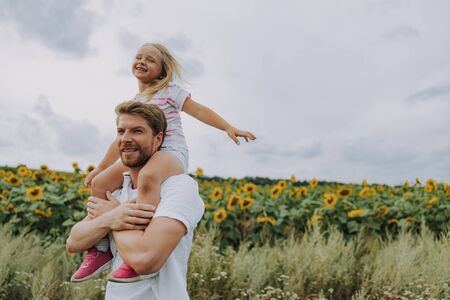Happy cheerful daughter having fun with her smiling dad outdoorsの写真素材