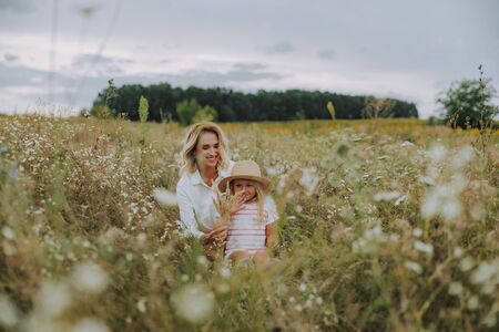 Charming lady hugging her small daughter in fieldの写真素材