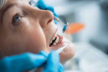 Close up of arms of dentist exploring mouth of happy womanの写真素材