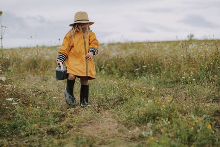 Happy little girl in raincoat walking outdoors