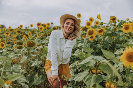 Young pretty lady spending time in sunflower field in summer