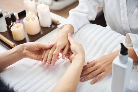 Beautician taking care of lady hands after manicure