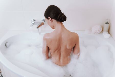 Rear view of a nude woman taking showerの写真素材